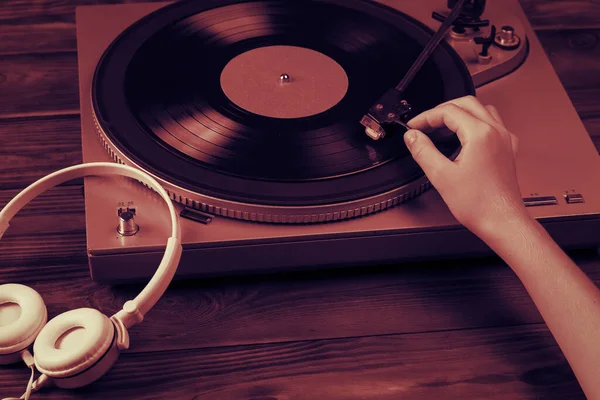 A tinted image of a hand placing a vinyl disc on the player. — Stock Photo, Image