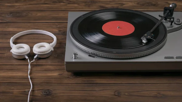 Un tourne-disque vinyle et des écouteurs sur une table en bois sombre. — Photo