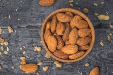 Tahta bir masanın üzerinde badem olan ahşap bir kâse..