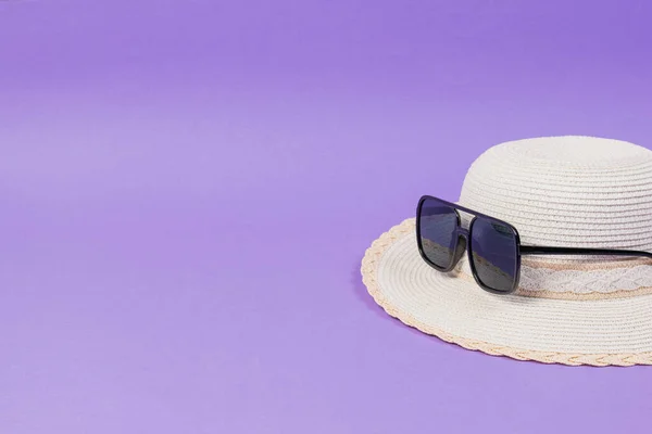 Stylowy letni damski kapelusz w okularach przeciwsłonecznych na liliowym tle. — Zdjęcie stockowe