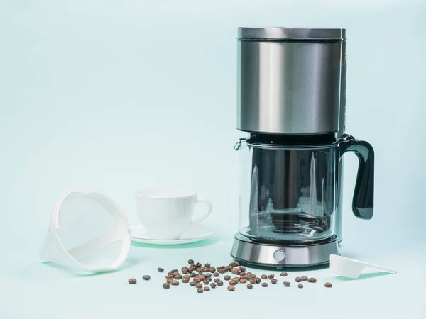 Cafetière, tasse, passoire et grains de café sur une table blanche. — Photo