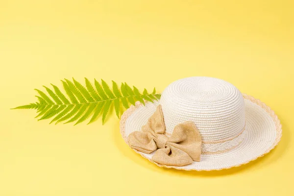 Duży biały kapelusz i liść palmowy na żółtym tle. — Zdjęcie stockowe