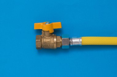 Mavi arka planda sarı hortumlu gaz musluğu.