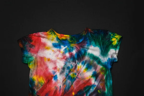 T-shirt multicolore tinta cravatta su sfondo nero. Posa piatta. — Foto Stock