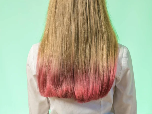 Una chica con el pelo teñido consejos sobre un fondo verde. — Foto de Stock