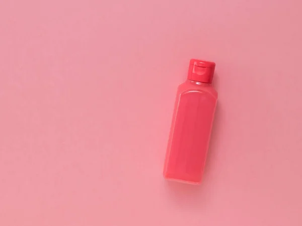 Una botella roja llena de líquido sobre un fondo rojo. — Foto de Stock