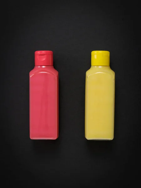 Bouteilles en plastique rose et jaune sur fond noir. — Photo