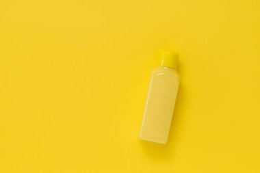 Sarı arkaplanda sarı sıvı olan sarı plastik bir şişe..