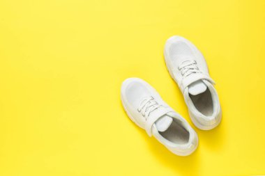 Sarı arka planda cırt cırtlı beyaz spor ayakkabılar. Spor tarzı. Düz yatıyordu.