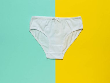 Sarı ve turkuaz arka planda şık beyaz kadın külotu. Düz yatıyordu.