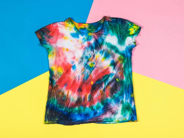 T-shirt em estilo tie dye em um fundo de três cores brilhantes. Depósito plano. — Fotografia de Stock