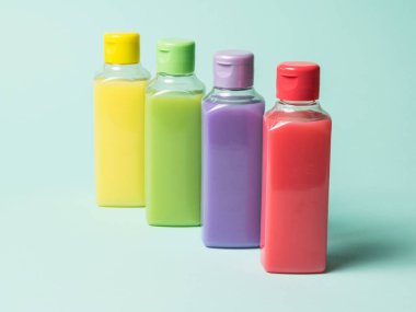 Hafif arka planda sıvı içeren renkli plastik şişeler..