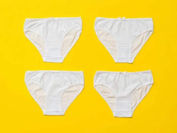Cuatro bragas de mujer blancas sobre un fondo amarillo. Puesta plana. —  Fotos de Stock