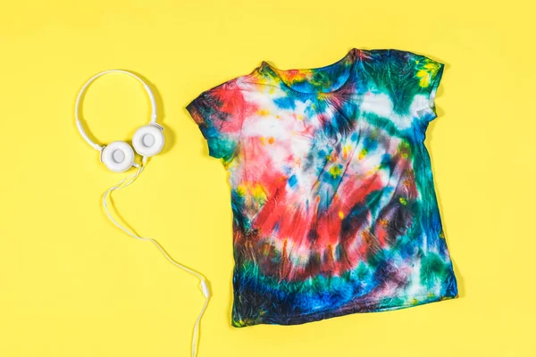 Κίτρινο φόντο με tie dye t-shirt και ακουστικά. Επίπεδη. — Φωτογραφία Αρχείου