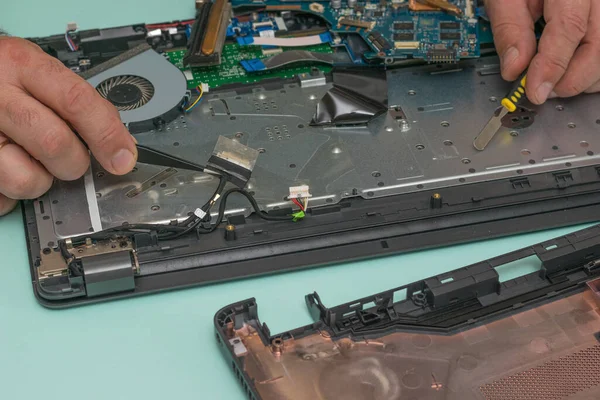 Un hombre conecta cables en la placa base de la computadora portátil. — Foto de Stock