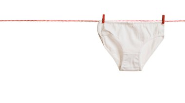 Beyaz arka planda izole edilmiş kırmızı beyaz bir iple kadın iç çamaşırları kuruyor..