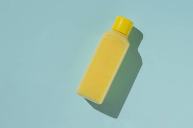 Mavi arka planda sıvı sabunla dolu sarı şişe..