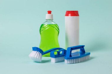 Açık arkaplanda üç mavi fırça, jöle ve temizlik tozu.