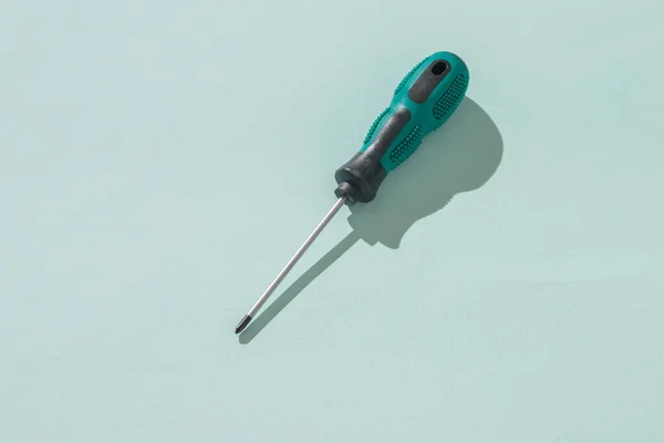 A screwdriver with a black and green handle on a blue background. — Stock Photo, Image
