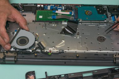 Bir adam dizüstü bilgisayarın soğutma vantilatörünü değiştiriyor..