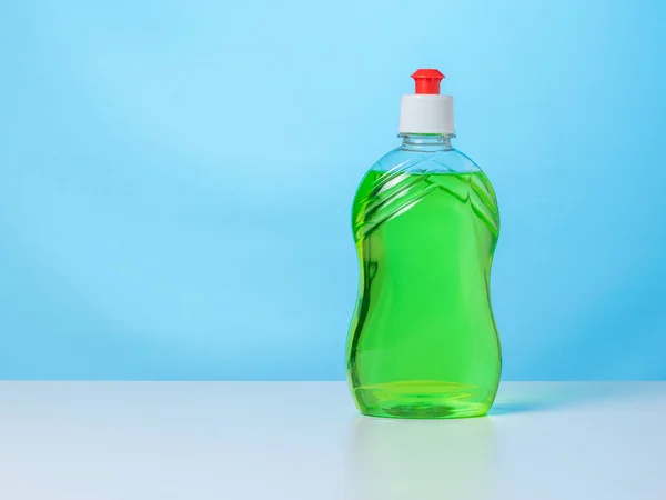 Láhev zeleného čisticího gelu na bílém stole na modrém pozadí. — Stock fotografie