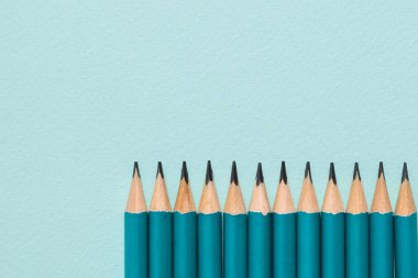 Mavi arkaplanda açılmış grafit kalemler.