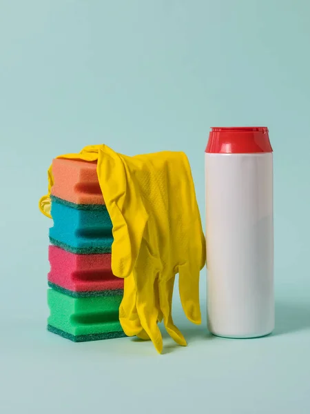 A stack of foam sponges, yellow gloves, and cleaning powder on a blue background.