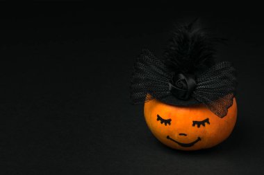 Siyah arka planda gözleri kapalı bir balkabağı.