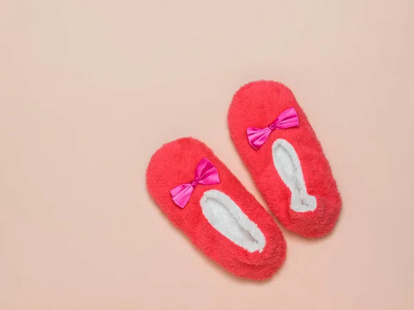 Red and white fur Slippers on a pink background.