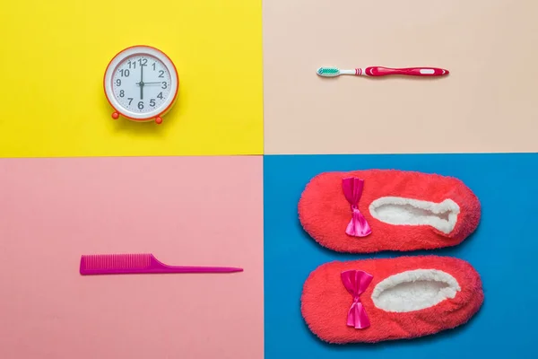 Inicio Zapatillas, despertador, cepillo de dientes y peine sobre un fondo de cuatro colores. — Foto de Stock