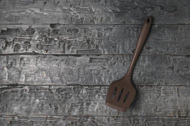Ahşap arka planda kahverengi silikon şef spatulası..
