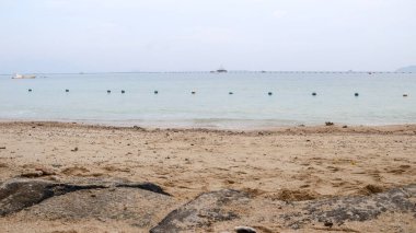 Bir dizi mavi ve beyaz şamandıra sessiz bir plajı kaplıyor. Yüzme alanlarını belirlemek için sınır işareti olarak kullanılır..