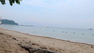 Bir dizi mavi ve beyaz şamandıra sessiz bir plajı kaplıyor. Yüzme alanlarını belirlemek için sınır işareti olarak kullanılır..