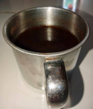 Paslanmaz çelik bir standın üstünde duran bir fincan sade kahvenin yakın çekimi..