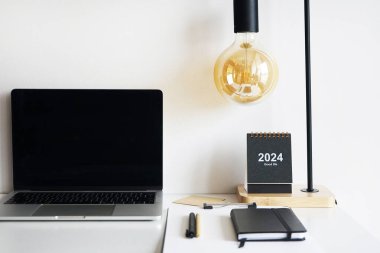 Lambalı masaüstü, kağıtlı klasör, not defterleri, kalemler, gözlükler, takvime beyaz arkaplan