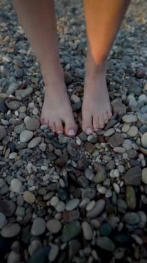 Çakıl taşlı sahilde yürüyen kadın bacakları.