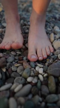 Kadının ayakları kumsalın çakıl taşlarında