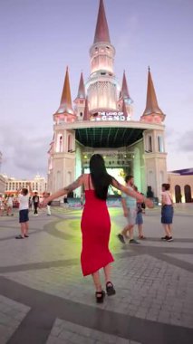 Şatonun yanındaki kırmızı elbiseli kadın turist.