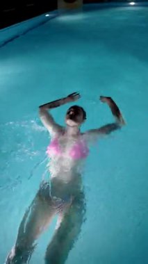 Havuzda sırt üstü yüzen bir kız.