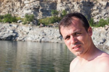 Bir arka plan taşları üzerinde Genç adam, su - yaz güneşli deniz