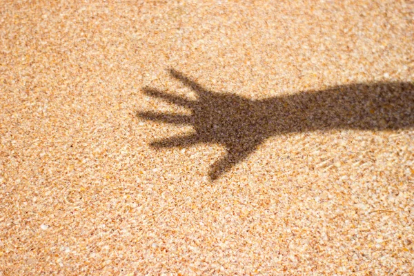 Sea water shadow from man\'s hand on sand background texture