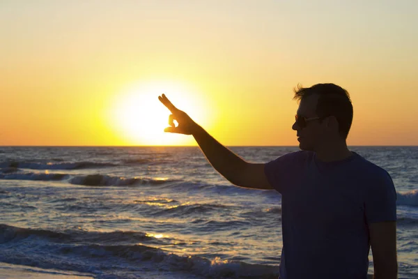 Молодой человек нажимает восход солнца фон голубое небо и море, пляж — стоковое фото