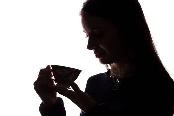 Silhuett av en ung kvinna med en kopp — Stockfoto