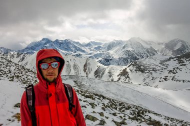 Bir sırt çantası ile bir miğfer Selfi erkek dağcı karlı dağlarda.