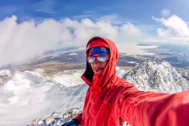 Bir sırt çantası ile bir miğfer Selfi erkek dağcı karlı dağlarda.