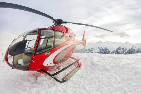 Röd rescue helikopter landar stående i snötäckta berg — Stockfoto