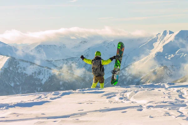 Snowboarder freerider is standing in the snowy mountains in winter under the clouds — Stock Photo, Image