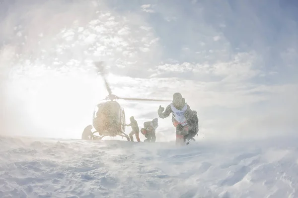 Aterragem a partir do helicóptero esquiadores freeriders nas montanhas nevadas no inverno — Fotografia de Stock