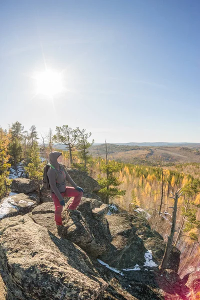 Frau mit Rucksack steht auf einem Felsen im Herbstwald — Stockfoto