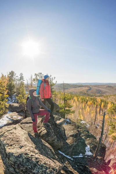 Coppia di turisti con zaini uomo e donna in piedi su una roccia in autunno panorama forestale — Foto Stock